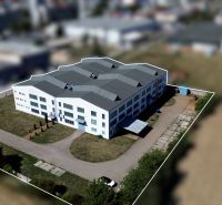 White industrial building in the area of Trenčín, K výstavisku street, surrounded by greenery.