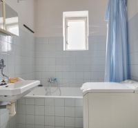 Bathroom with a bathtub, sink, washing machine, and blue shower curtain in a family house.