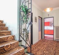A hallway with a staircase and colorful kitchen doors in a family house.