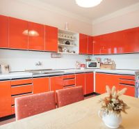 A kitchen in a family house with red cabinets and a dining table.