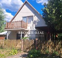 A cottage in Abaújkér with a wooden fence and abundant greenery in the garden.