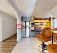 A kitchen with bar stools and a kitchen unit in a two-room apartment.