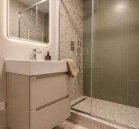 Bathroom with a sink, shower corner, and illuminated mirror in a 3-room apartment.