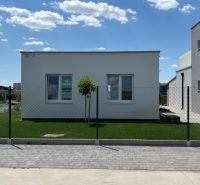 A family house in Boldog with a green lawn, surrounded by a fence and with a paved walkway.