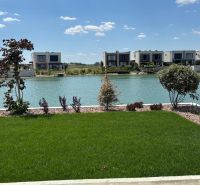 A family house in Boldog with a garden by the lake and a green lawn.