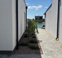 A narrow path between two family houses in Boldog leads to the lake at the end.