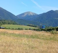 Recreational lands near the town of Turany with a mountain range and a truck on the road.