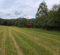 Recreational land in Turany with a wooden cottage, surrounded by nature and mountains.