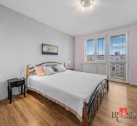 Bedroom with a double bed in a 3-room apartment, wooden decor flooring, bright room.