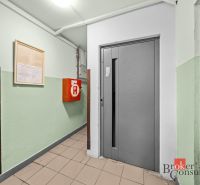 Elevator in the hallway of an apartment building, next to it is a fire cabinet.
