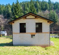 A family house in Lazy pod Makytou surrounded by a forest and other houses on a green plot.