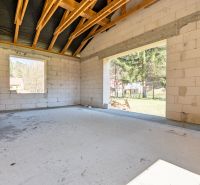 The interior of a family house with unfinished walls and a view of the garden.