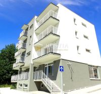 A four-story apartment building in Senica with balconies and a staircase, offering three-bedroom apartments.