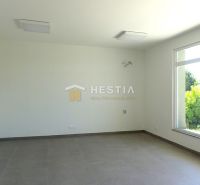 A spacious room with a large window, light-colored walls, and a floor with a wooden decor.