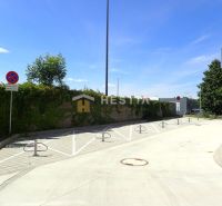 Parking lot by a 3-room apartment in Senica, with traffic signs and fencing.