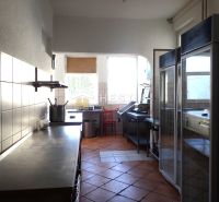 A kitchen in commercial premises with tiles and equipment.