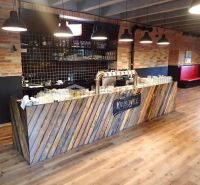 A bar counter in commercial premises with a wooden decor floor and a brick wall.