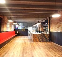 Commercial space with brick walls, a red bench, and a wood-patterned floor.