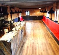 Commercial space with a bar and benches, wooden decor flooring, brick interior.
