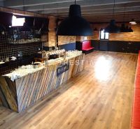 Commercial premises with a bar and wood-patterned flooring, red seating.