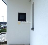 A family house in Hlboké with a white facade and a small window by the entrance.