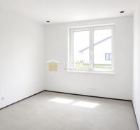 An empty room in a family house with white walls and a floor-to-ceiling window.