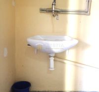 A sink with a blue bucket in the bathroom of a family house.