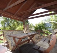 Covered terrace at a family house in Badín with wooden seating and garden vegetation.