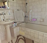 A bathroom in a family house with a sink, a bathtub, and ceramic tiles.