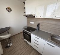 A kitchen in a 2-room apartment with a wooden decor floor and a modern kitchen unit.