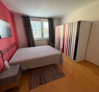 A bedroom in a two-room apartment with a colorful wardrobe and a wooden decor floor.