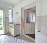 A kitchen in a family house with white walls and a tiled floor.