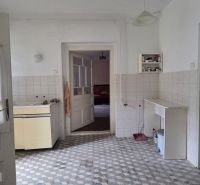 A kitchen in a family house with a tiled floor and simple furnishings.