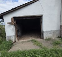 A family house in the village of Boldogkőújfalu with an abandoned garage and an overgrown garden.