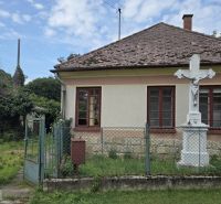 A family house in Boldogkőújfalu with a simple facade and a stone cross in the garden.
