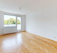 A bright room with wood-decor flooring in a three-room apartment.