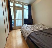 Bedroom in a 2-room apartment with a bed, wardrobe, and floor with wooden decor.