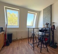 A kitchen in a 2-room apartment with a wooden decor floor and skylights.