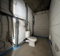 Unfinished commercial space with sanitary facilities, concrete walls, and floor.