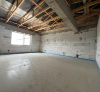 The interior of commercial premises with an unfinished floor and raw brick walls.