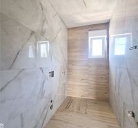 A bathroom in a 3-room apartment with marble tiles and a wooden decor floor.