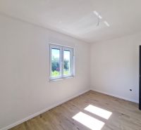 A white room in a 3-room apartment with a wood-patterned floor and a window.