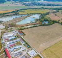 Aerial view of warehouses and halls in Dulov surrounded by fields and water bodies.