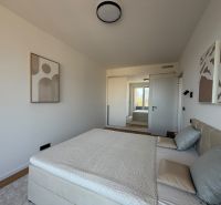 A bedroom in a two-room apartment with a wooden decor floor, cozily furnished.