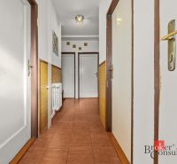 A corridor with white walls and doors in a 3-room apartment, brown tiles.