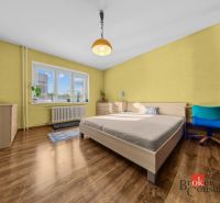 A kitchen in a 3-room apartment with a refrigerator, dining table, and wooden decor flooring.