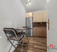 A kitchen in a 3-room apartment with a kitchen unit, appliances, and a floor with a wood decor.