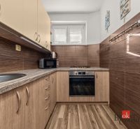 A kitchen in a 3-room apartment with a wooden decor floor and appliances.