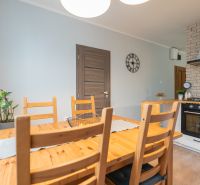 Dining area in a 3-room apartment with a wooden table, brick cladding, and a clock on the wall.