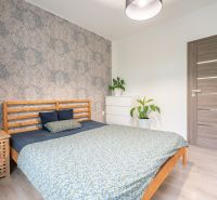A bedroom in a 3-room apartment with floral wallpaper and a wooden decor floor.